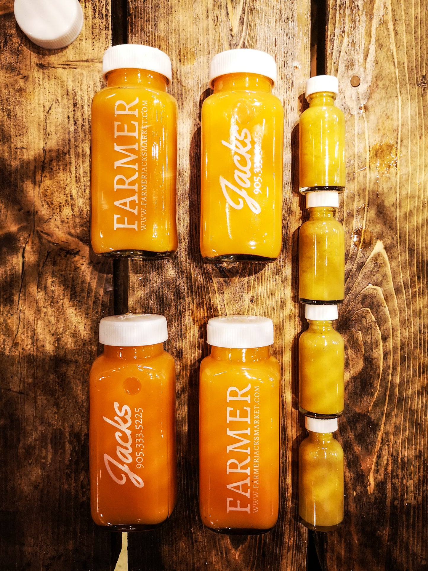 Farmer Jack's Booster Pack - 4x 250ml glass bottles of bright orange Immunity Booster juices, and 4x 1oz bottles of bright yellow Flu Shots.