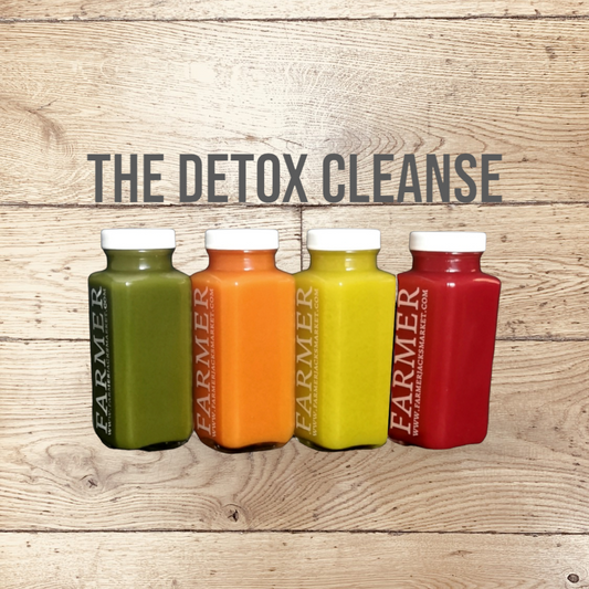 Farmer Jack's Detox Cleanse image - 4 gleaming glass bottles, stamped with Farmer Jack's branding, which pops against the brightly coloured juices within them.